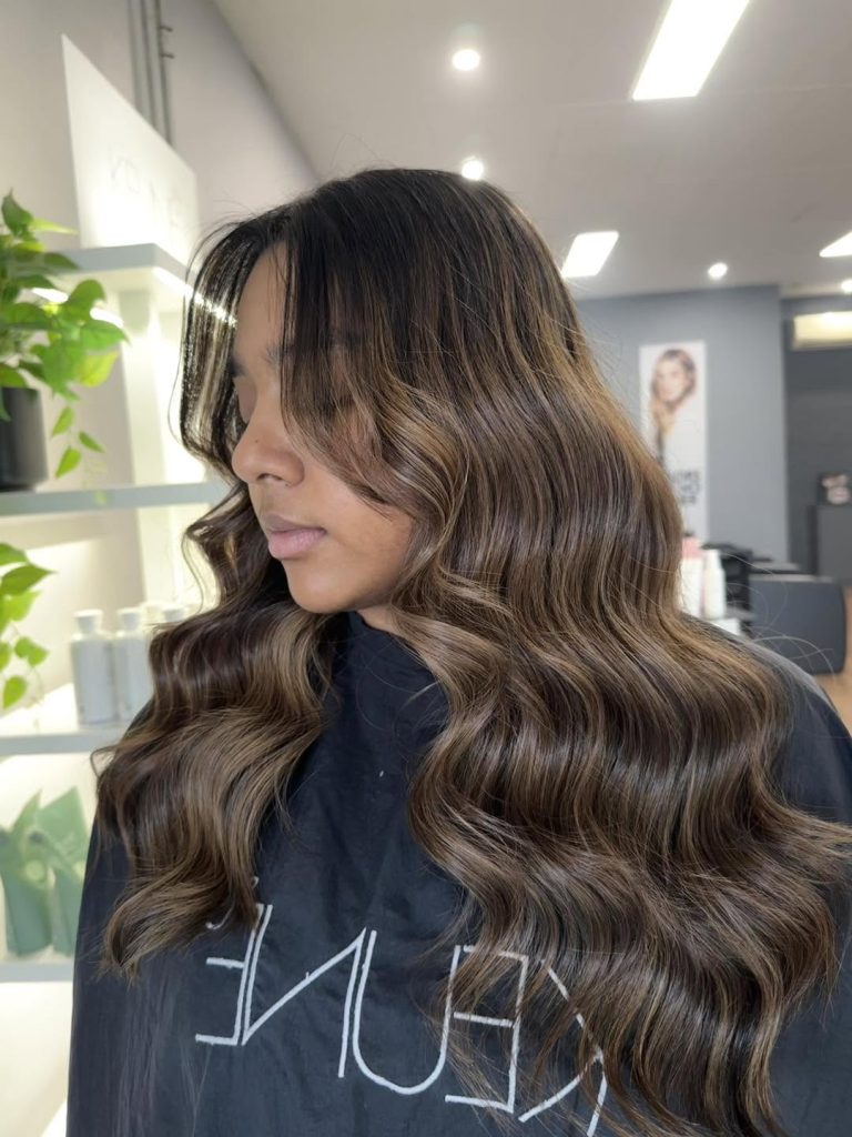 Long brunette hair with soft dimensional highlights and waves at Hair Envy Wallacia